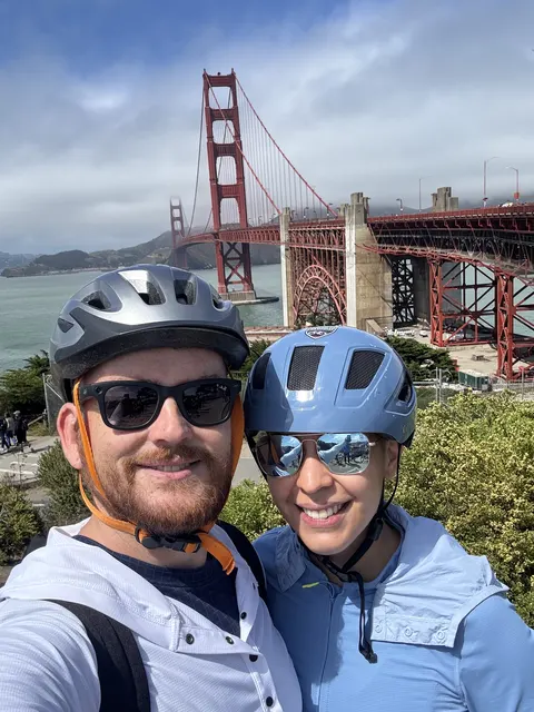 Nate and Angie wearing bike helmets in front of the Golden Gate Bridge