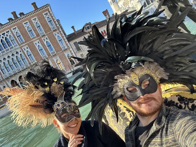 Nate and Angie wearing elaborate masks beside a Venetian canal